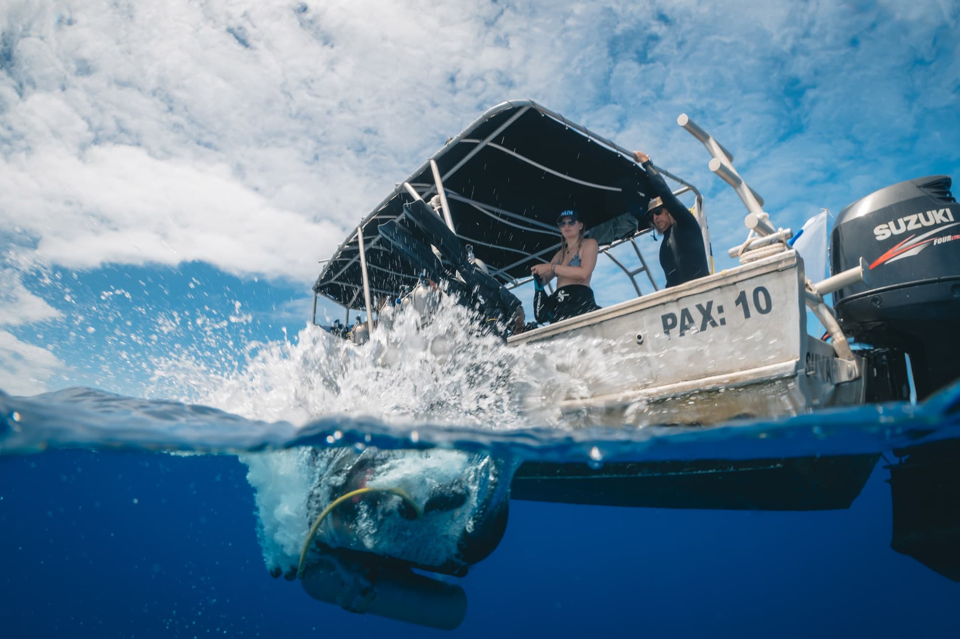 Bateau de plongée en surface et tortue marine nageant sous la coque